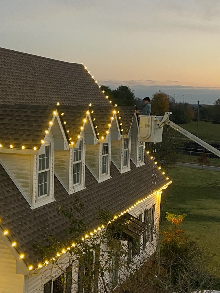 Hanging christmas lights on a roof from a bucket truck